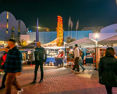 People walking with vendor tents in the background